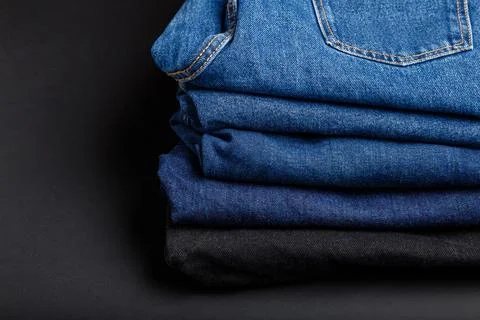Blue jeans trousers stack. Stack of blue jeans on black background with copy Stock Photos
