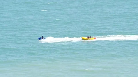 Blue jet ski pulling yellow raft along ocean water having fun entertainment Stock Footage 205449783