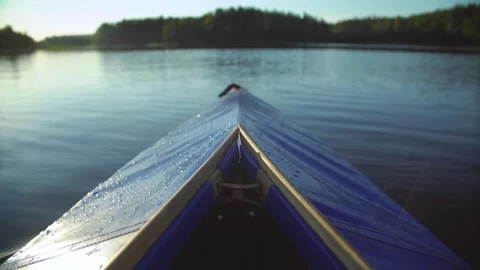 Blue kayak moving through calm lake water at sunset Stock Footage 333835289