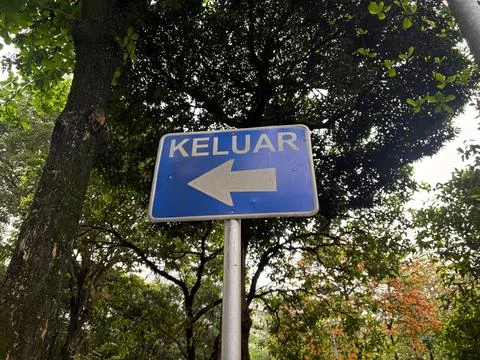 Blue keluar exit sign with left arrow in garden directional navigation Stock-Fotos
