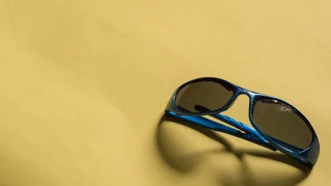 Blue kid plastic glasses on yellow background Stock Photos