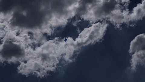 Blue kite flying on a blue sky and cloudy day Stock Footage 77196137