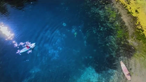 In the blue lagoon, divers rise to the surface and people on SUP boards float. 스톡 동영상 165324938