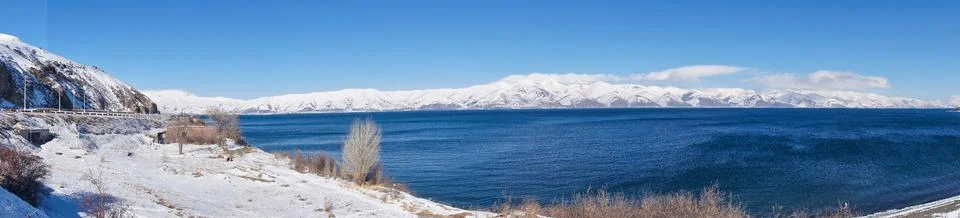 Blue Lake Sevan on the background of snow-capped mountains on a sunny day Stock Photos