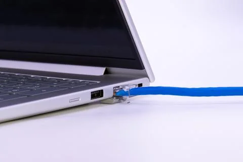 Blue lan cable connected to laptop ethernet port showing stable wired Stock Photos