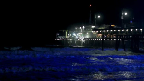 Blue lights on ocean waves next to pier Stock Footage 99316553