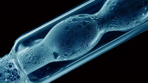 Blue liquid condensing on bulb lab condenser black background Stock Footage 338346661