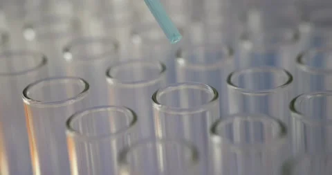 Blue liquid drops fall from pipette into test tubes put in row Stock Footage 307902213