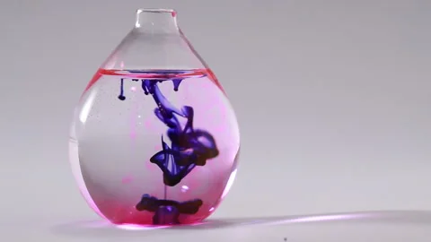 Blue liquid going down throughout pink water on a flat bottomed flask Stock Footage 231488019