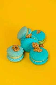 Blue macaroons on a yellow plain background, with walnuts Stock Photos