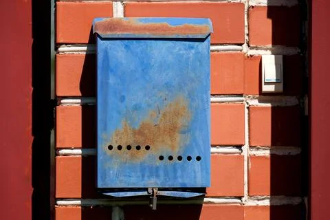 A blue mailbox hangs on a red brick wall outside. Russian post box Stock Photos