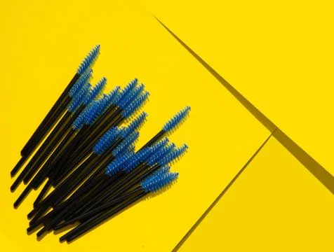 Blue makeup brushes, combs for eyelashes and eyebrows on a yellow background Stock Photos