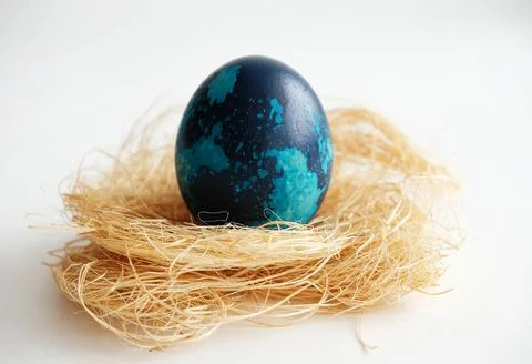Blue marbled Easter dyed egg on coconut fiber on a white background close up Stock Photos