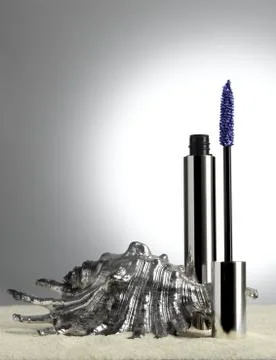 Blue mascara wit silver shell on sand Stock Photos