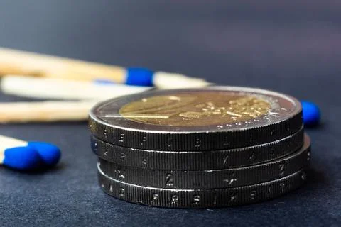 Blue matches and stack of coins on dark background macro Stock Photos
