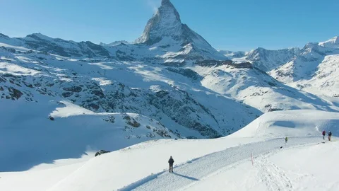 Blue Matterhorn Mountain in Winter Day and Hiker Man. Switzerland. Aerial View Stock Footage