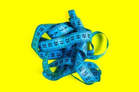 Blue measuring tape on a yellow background. Diet concept. Stock Photos