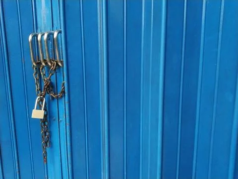 Blue metal door secured with multiple padlocks and chains, symbolizing secu.. Stock Photos
