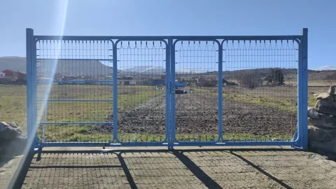 Blue metal gate slowly opening to a rural landscape Vídeo Stock 340326351