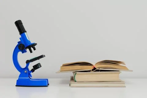 Blue microscope and books on table Stock Photos