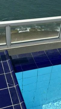 Blue mind reset at rooftop pool corner with deep blue tiles and ocean below.. Stock Photos