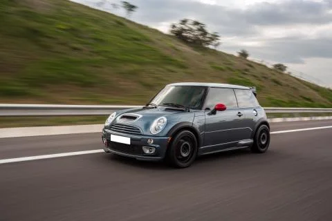 Blue mini cabriolet on the highway in a cloudy day Stock Photos
