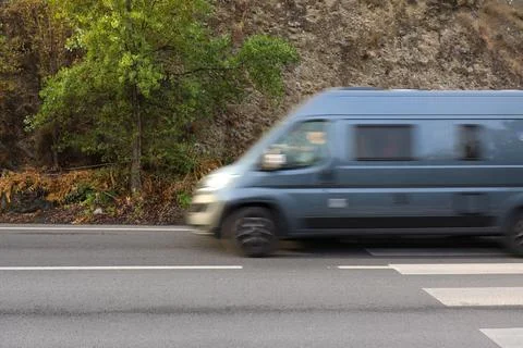 Blue Mini Van on a High Speed On the Street with Stones Hill as the Background Stock Photos