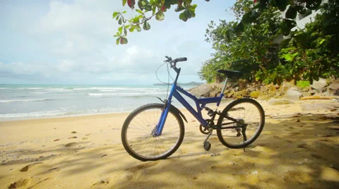 Blue modern mountain bike parked on a tropical beach Stock Footage 32349341