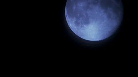 Blue moon glowing moves through dark night sky frame Stock Footage 329656895
