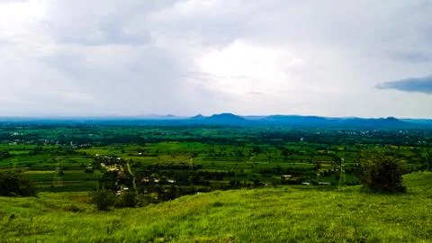 Blue mountain wide angle view from green plateau in cloudy sky Stock Photos