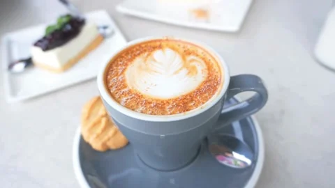 A blue mug of Frothy drink on the table at coffee shop. 動画素材 334648720
