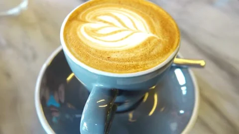 A blue mug of Frothy drink on the table at coffee shop. Stock-Footage 334648730