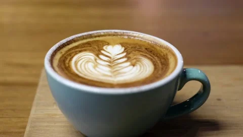 A blue mug of Frothy drink on the table at coffee shop. Stock-Footage 334648800