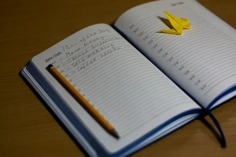 Blue notebook with notes with a pencil, yellow paper crane on the diary. Foto stock