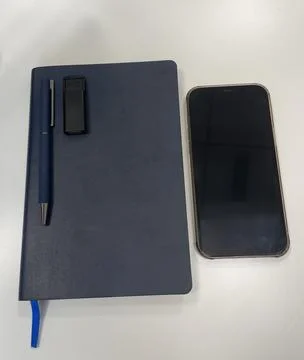 A blue notebook, a pen, a USB flash card, and a smartphone Stock Photos