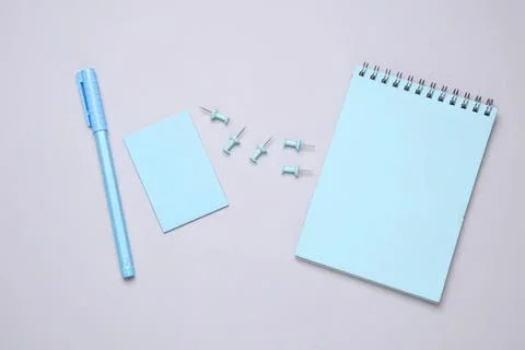 Blue notepad with pen and push pins on light background Stock Photos