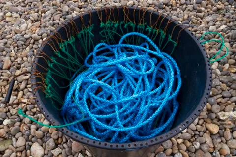 Blue nylon rope, black bin, pebbled beach Stock Photos