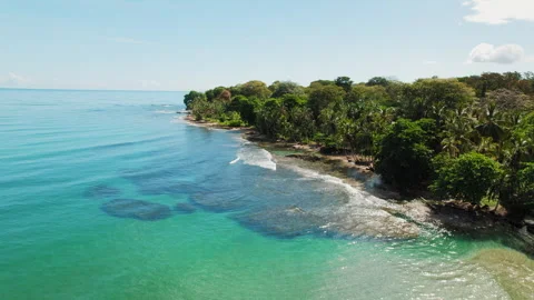 Blue ocean coastline with lush forest meeting shallow reef waters in Costa Rica Stock-Footage 326009302