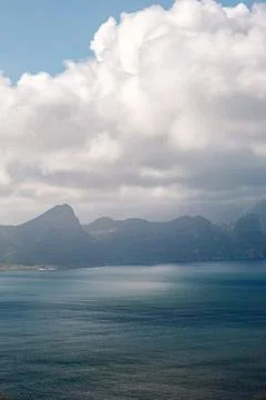 Blue ocean with mountain range in background on partly cloudy day, South Afri Stock Photos