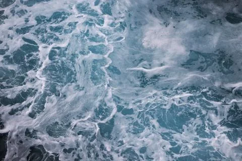 Blue ocean waves creating white foam seen from above. Foto stock