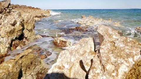 Blue ocean waves gently crashing onto a rocky coastal shore. Stock Footage 337406243