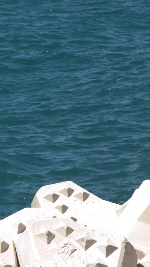Blue Ocean Waves Rippling Against Concrete Tetrapod Breakwater Seawall Video stock 338327101