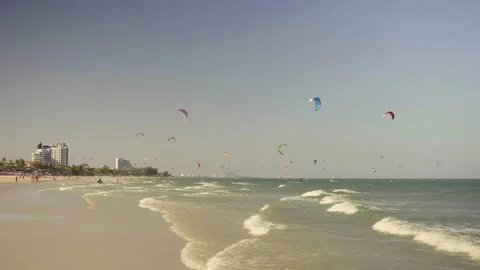 Blue ocean waves roll on sandy beach and kitesurfers in sky Stock Footage 133125160