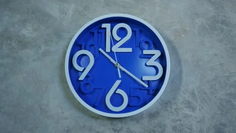 A blue office clock hangs on a gray concrete wall. Time lapse, timelapse Stock Footage