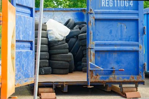 Blue open container filled with stacked old car tires for recycling. Stock Photos
