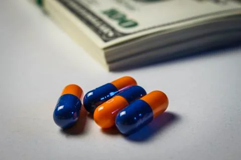Blue-orange capsules and on the table with a pack of dollars Stock Photos