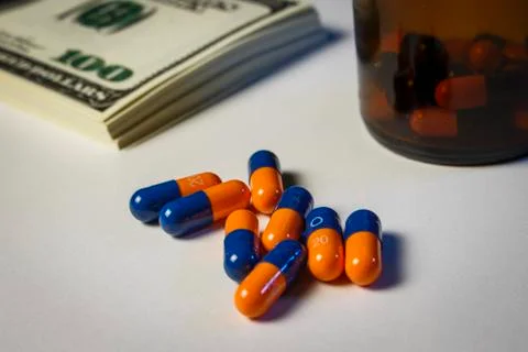 Blue-orange capsules on the table with a pack of dollars Stock Photos