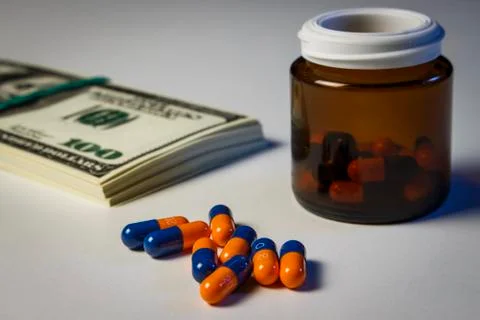 Blue-orange capsules on the table with a pack of dollars Stock Photos