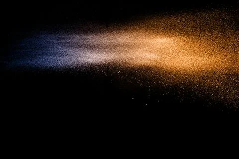 Blue orange dust particles explosion on black background. Color powder dust.. Stock Photos