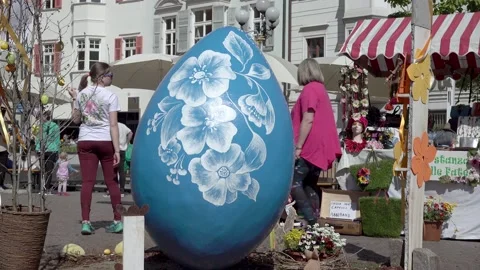 A blue oversized Ester egg at an Easter market. People walking past it. Stock Footage 197805099